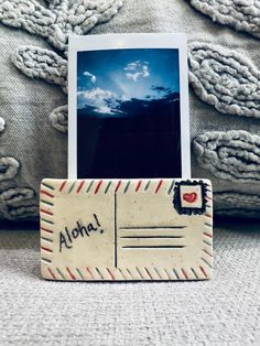 an old fashioned photo frame with the word aloha on it sitting next to a pillow