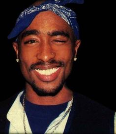 a man wearing a blue bandana smiles at the camera