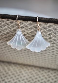 Beautiful and feminine Art Deco fan-shaped white mother of pearl earrings. The pearl has an incredible sheen and take on a subtle glow when they catch the light. They are finished with 14 k gold filled, 14 k rose gold or sterling silver simple earwires. Simple and elegant, you will not go unnoticed. The perfect earrings for a gift or to treat yourself. Ideal for a wedding, and bridesmaids. Made using the highest quality USA and UK sourced materials. *Remember photo can make pieces look larger, please see the "DETAILS" for measurements. Please note that as this is a natural stone, each stone is unique and has its own individual characteristics.  All stones are selected individually and are matched by hand. Natural variations in size, color, cut and clarity are typical and add to the unique Elegant Shell-shaped Wedding Earrings, Elegant Shell-shaped Mother Of Pearl Earrings, Elegant Mother Of Pearl Shell Earrings, Elegant Shell-shaped Pearl Earrings In Mother Of Pearl, Elegant Shell Earrings For Gifts, Elegant Shell-shaped Pearl Earrings For Wedding, Mother Of Pearl Jewelry For Pierced Ears For Weddings, Mother Of Pearl Earrings For Wedding, Handmade White Mother Of Pearl Earrings