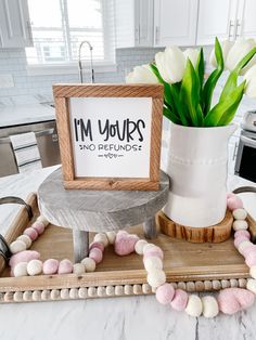 a white vase filled with flowers on top of a wooden tray