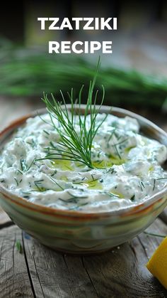 a bowl of tzatzziki dip with dill sprigs on top