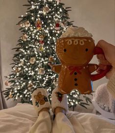 someone is holding a gingerbread man ornament in front of a christmas tree