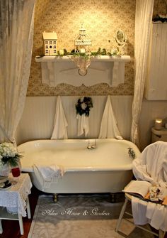 a white bath tub sitting under a window next to a table with flowers on it