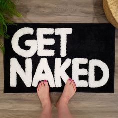 a woman's feet on a rug that says get naked