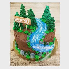 a cake decorated with trees, rocks and a river in the middle that says mile 50