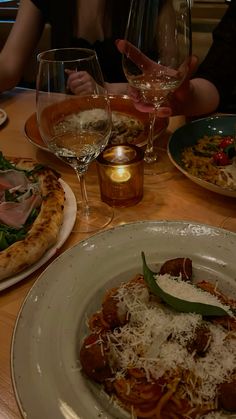 people sitting at a table with plates of food and glasses of wine