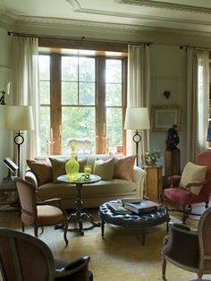 a living room filled with lots of furniture next to a window covered in drapes