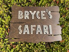 a wooden sign that says bryce's safari on top of some bushes