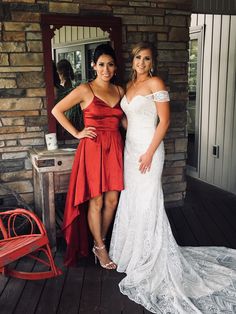 two women standing next to each other in front of a brick wall and red chair