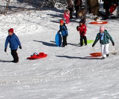 several people are skiing and snowboarding in the snow with one person pulling a sled behind them