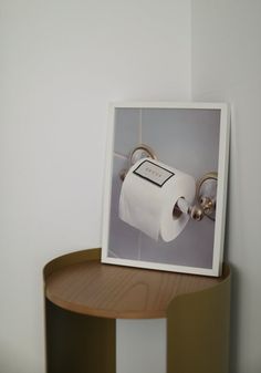 a photograph of a roll of toilet paper on a shelf next to a round table