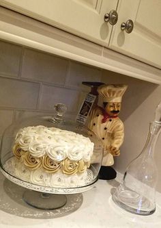 a cake sitting on top of a counter next to a vase and glass container filled with flowers