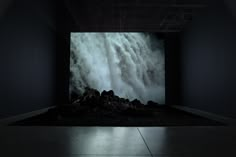 an image of a large waterfall in the middle of a room with rocks on the floor