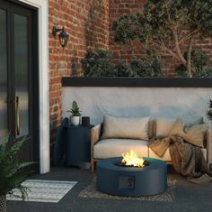 a white fire pit sitting on top of a patio next to a tree and potted plants