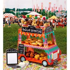 a food stand with donuts and other foods on it at an outdoor event in the grass