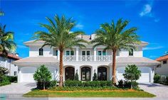 a large white house with palm trees in the front yard