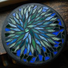 a round stained glass plate sitting on top of a wooden table next to a window