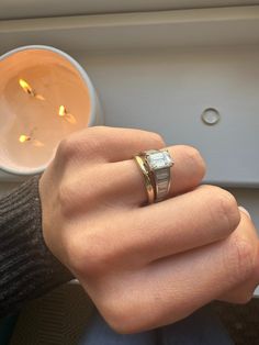 a person's hand with a ring on it next to a candle