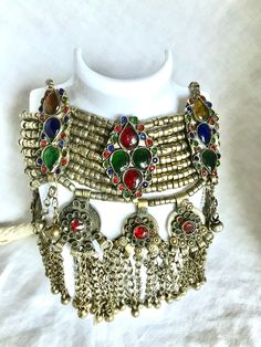 "Please Read Full Description This is a gorgeous vintage brass choker necklace originating from India.  This necklace has nine strands of metal beads that are connected to a braided cotton cord for tying around the neck.  It is adorned with colored stones throughout and medallion tassels that are attached with tiny bells on the end.  Such a beautiful statement piece! The condition of this piece is very good for its age.  All of the larger stones are intact, but there are several small stones missing from the medallion tassels.  Please see/zoom photos for a closer look. Measurements:  Necklace 11\" Wide (33\" including tie)  x  Approx. 6\"  Long FREE DOMESTIC SHIPPING My vintage finds are all pre-owned and pre-used.  Please expect your item to show signs of both.  I inspect all of my items Bohemian Metal Jewelry With Large Beads, Vintage Jewelry With Large Beads For Festivals, Bohemian Jeweled Choker Necklace, Vintage Jeweled Jewelry For Festivals, Adjustable Bohemian Jewel Necklace, Adjustable Bohemian Jewel Necklaces, Bohemian Adjustable Jeweled Necklaces, Bohemian Adjustable Jewel Necklaces, Adjustable Jeweled Festival Jewelry