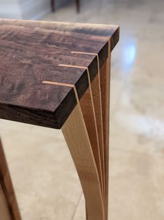 a close up of a wooden table with some lines on it's edge and two chairs in the background