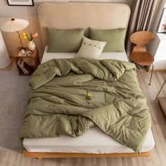 a bed with green comforter and pillows in a room