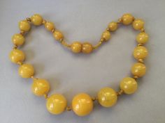 "Lovely egg yolk Bakelite single strand necklace. Hand tied graduated beads. Romantic, yellow necklace. Hidden bead clasp. Simply beautiful, gleaming, set of beads. Large knot, hand tied 1930s style. Chunky! Graduated beads: 8mm (smallest) to 17mm (largest) 15 1/2\" necklace Attention: All items are listed to the best of our observation, but they are pre-owned and pre-loved (meaning we may have missed something minor and/or be in need of light cleaning.) Please read our shop policies and/or conv Classic Yellow Round Bead Jewelry, Yellow Costume Jewelry Necklace For Formal Occasions, Yellow Costume Jewelry Necklace For Formal Events, Formal Yellow Jewelry With Round Beads, Vintage Polished Yellow Beads Jewelry, Yellow Single Strand Beads For Jewelry Making, Vintage Yellow Jewelry With Polished Beads, Yellow Single Strand Necklace For Jewelry Making, Vintage Yellow Single Strand Jewelry