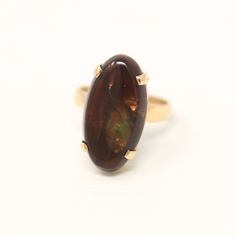 Unique estate 14k yellow gold genuine fire agate ring! This amazing statement ring features an oblong oval shaped fire agate that weighs approximately 4.93 carats. The dark reddish brown hued gem displays an iridescence of colors and is secured with four single prongs. A exceptional piece of fine jewelry, featuring a remarkable gemstone! *Sale - price reduced from $750 USD to $740 USD.  ERA - Circa 2000, Modern  METAL / MATERIAL - 14k yellow gold, 1 genuine fire agate (approx. 4.93 cts). MARKING Modern Oval Opal Ring For Formal Occasions, Modern 14k Gold Oval Opal Ring, Classic Oval Opal Ring Collectible, Heirloom Oval Opal Ring With Polished Finish, Fire Agate Ring, Brown Gemstone, Logo Gifts, Fire Agate, Agate Ring