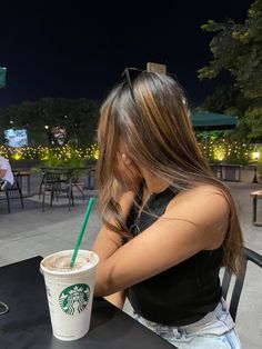 a woman sitting at a table with a starbucks drink