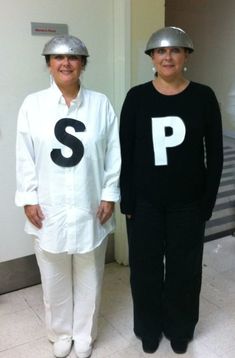 two women standing next to each other in front of a door with letters painted on them