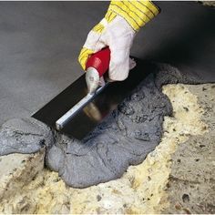 a person using a trowel to put cement into a hole in the ground