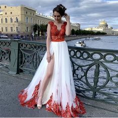 a woman in a red and white dress standing on a bridge with her legs crossed