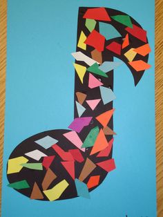 the letter j made out of colored paper on a blue background with a wooden table