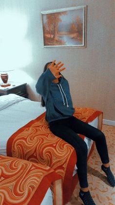 a woman sitting on top of a bed in a room with orange bedspreads