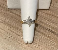 a diamond ring sitting on top of a white napkin next to a wooden tablecloth