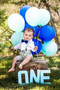 a little boy sitting on top of a crate holding blue and white balloons with the words, nathan jameson ledgeer