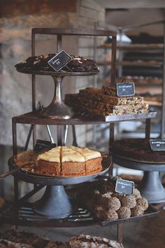 three tiered trays filled with different types of cakes and pastries on top of each other