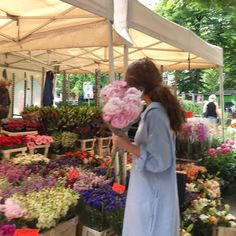 a woman is looking at flowers for sale