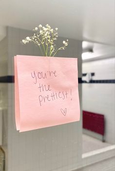 a post it note attached to a glass door with flowers in the middle and you're the prettiest written on it