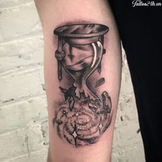 a black and white tattoo on the arm of a man with an hourglass in his head