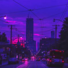 a city street at dusk with cars driving on the road and buildings in the background