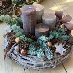 some candles are sitting in a basket with pine cones and other decorations on the table