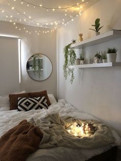 a bedroom with lights strung from the ceiling and plants on the shelves above the bed