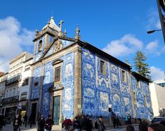 many people are walking around in front of a building with blue and white tiles on it