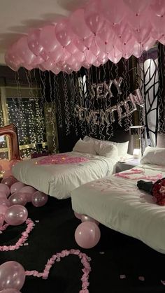 two beds in a room with pink balloons and streamers on the wall above them