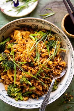 a bowl filled with rice and broccoli next to chopsticks on a table