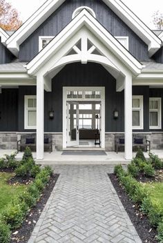 a black and white house with an entry way leading to the front door that is flanked by two benches