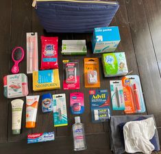 the contents of a travel bag laid out on top of a wooden floor next to a blue purse