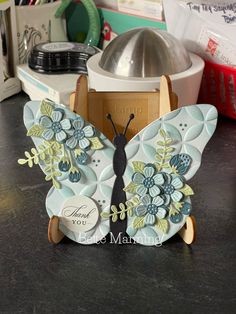 a close up of a butterfly on a table with other items in the back ground