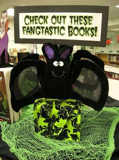 a stuffed bat sitting on top of a green net next to a sign that says check out these fantastic books