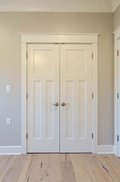 an empty room with two white doors and hard wood flooring